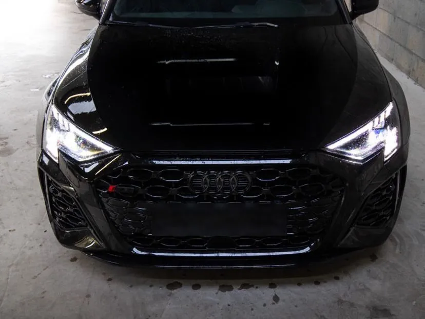 Audi RS3 noire vue de face, phares allumés
