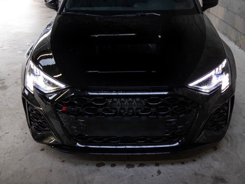Audi RS3 noire vue de face, phares allumés
